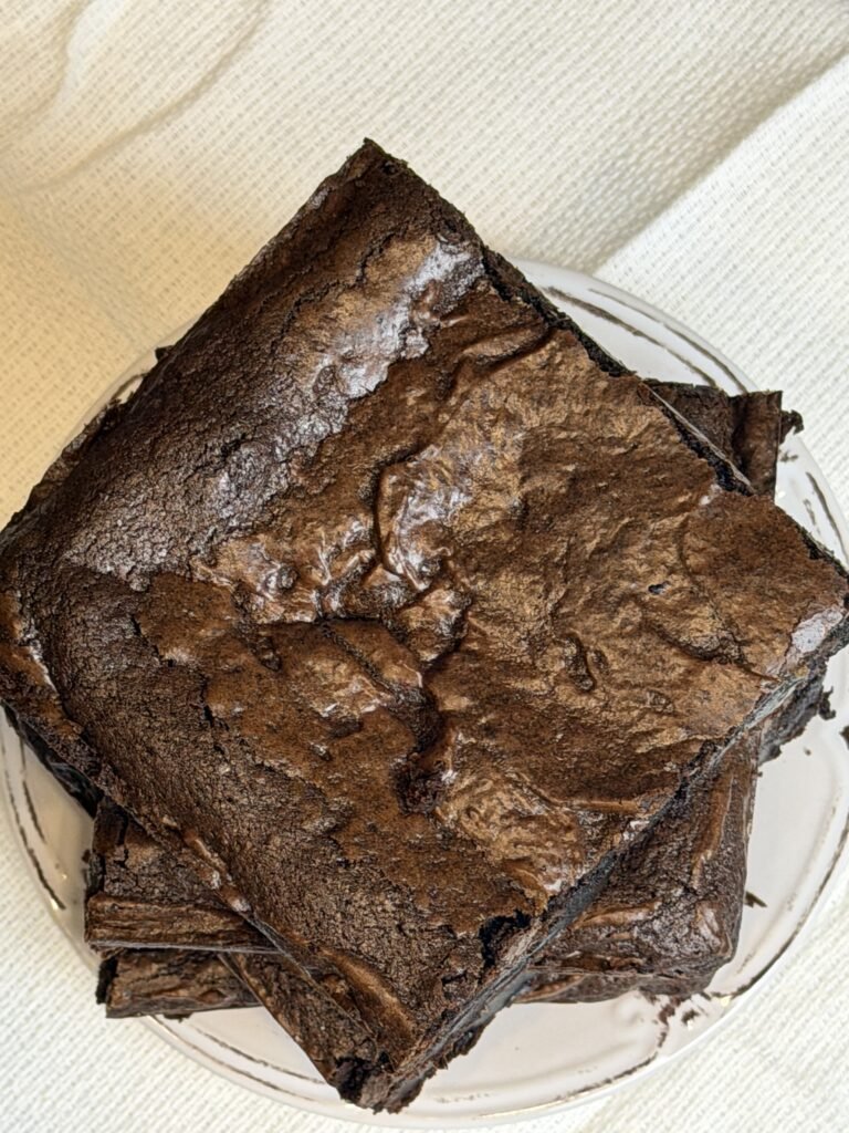 A stack of fudgy brownies squares on a white plate.