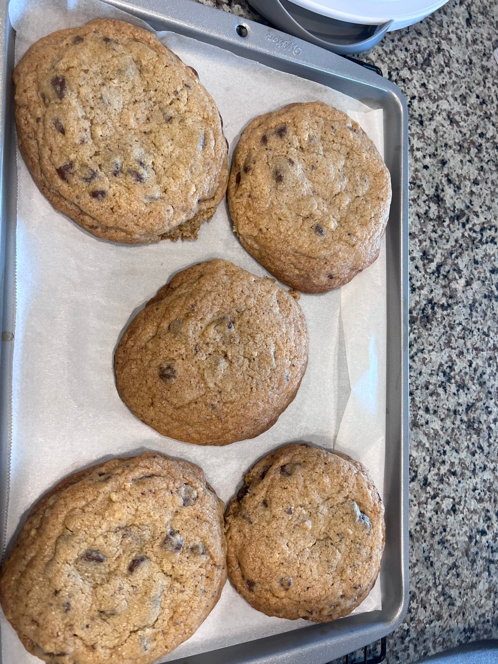 five flat cookies on a small baking sheet
