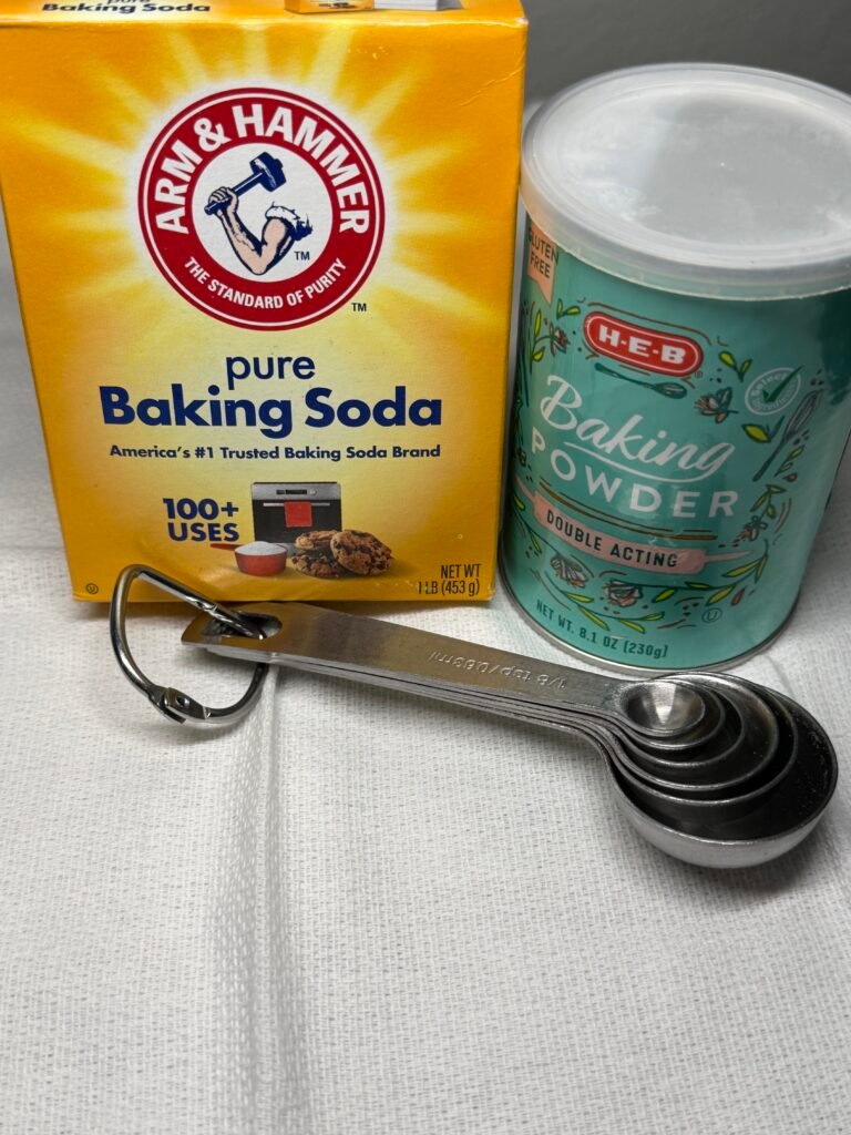 Baking Soda and Baking Powder on a table with measuring spoons next to them...